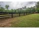 Fenced yard with a view of green grass, mature trees, and a red outbuilding at 7505 Rico Rd, Chattahoochee Hills, GA 30268