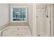 A bathtub is beside a shower and window at 327 Oakland Bay Ct, Loganville, GA 30052