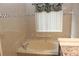 A tiled bathroom featuring a soaking tub under a window with a decorative curtain at 5574 Mccrossin Cir, Lithonia, GA 30038