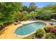 A large in-ground pool features a stone patio, wood deck, lounge chairs and lush landscaping at 4820 Coppedge Trl, Peachtree Corners, GA 30096