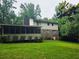 Back of home with a screened porch, brick chimney, and lush green lawn at 2553 Country Club Dr, Conyers, GA 30013