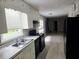 Functional kitchen with black appliances, white cabinets, and updated counters with window above sink at 2553 Country Club Dr, Conyers, GA 30013