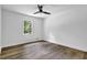 Bright bedroom features wood-look flooring, a ceiling fan, and a window with views of lush greenery at 5666 Fawn Dr, Powder Springs, GA 30127