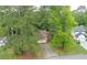 Aerial view of the home, showing a driveway, two car garage, brick chimney, and wooded surroundings at 9383 Woodknoll Way, Jonesboro, GA 30238