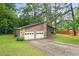 Home exterior features a two-car garage, wood siding, stone accents and a long driveway at 9383 Woodknoll Way, Jonesboro, GA 30238
