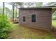 Side exterior view showcasing the home's siding, two windows, and a glimpse of the wooded yard at 9383 Woodknoll Way, Jonesboro, GA 30238