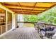 Enjoy grilling in this covered wooden porch overlooking the fenced backyard with lush greenery for outdoor relaxation at 2200 E Lake E Rd, Mcdonough, GA 30252