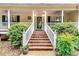 Inviting front porch with brick stairs, a white railing and lush landscaping at 2200 E Lake E Rd, Mcdonough, GA 30252