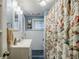 Bright bathroom featuring floral shower curtain, white vanity, tiled walls, and a window for natural light at 4611 Dogwood Rd, Pine Lake, GA 30072