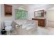 Bathroom with a relaxing tub, vanity with double sinks, and a window offering a view of the green outdoors at 48 Saddle Field Nw Cir, Cartersville, GA 30121