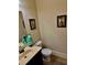 Half bathroom with modern vanity, framed mirror, decorative artwork, and beige tile flooring at 520 Harmony Way, Locust Grove, GA 30248