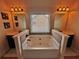 Bathroom with large soaking tub in the center, flanked by vanities, and natural light from the window at 520 Harmony Way, Locust Grove, GA 30248