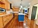 Well-lit kitchen with a blue island, hardwood floors, modern appliances, and light wood cabinets at 722 Beauregard Sw Dr, Marietta, GA 30064