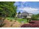 Large backyard featuring a patio, lush lawn, mature trees, and landscaped garden beds at 1997 Shaker Falls Ln, Lawrenceville, GA 30045
