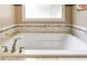 Close-up of a soaking tub with tile surround, brushed-nickel fixtures and natural light from a window at 1997 Shaker Falls Ln, Lawrenceville, GA 30045