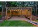 Charming backyard pergola with string lights, benches, and stone landscaping features for relaxation at 735 River Ridge Ln, Suwanee, GA 30024