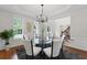 Dining room with abundant light, modern chandelier, round glass table, wainscoting, and hardwood floors at 735 River Ridge Ln, Suwanee, GA 30024