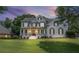 Elegant white brick home with covered porch and black shutters, beautifully lit during twilight at 735 River Ridge Ln, Suwanee, GA 30024