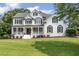 Elegant white brick home featuring a covered front porch, black shutters, and lush green lawn at 735 River Ridge Ln, Suwanee, GA 30024