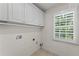 Bright laundry room features upper cabinets and a window with natural light at 735 River Ridge Ln, Suwanee, GA 30024