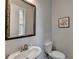 A half bathroom showing the mirror, sink, toilet and artwork at 747 Topsail Ln, Alpharetta, GA 30005