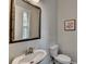 Powder room featuring a pedestal sink, toilet, decorative mirror, and wall art at 747 Topsail Ln, Alpharetta, GA 30005