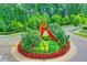 Beautiful landscaped roundabout with colorful flowers, shrubbery, trees, and an interesting sculpture in the center at 747 Topsail Ln, Alpharetta, GA 30005
