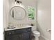 Stylish bathroom featuring a dark vanity with a round mirror and modern fixtures at 10645 Tuxford Dr, Alpharetta, GA 30022