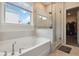 Bright bathroom featuring a soaking tub, glass shower, and natural light from a window at 1504 Lemon Balm Ct, Lawrenceville, GA 30045