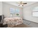 Bright bedroom with a floral comforter, ceiling fan, and natural light from two windows at 1504 Lemon Balm Ct, Lawrenceville, GA 30045