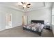 Primary bedroom with ensuite bathroom and closets. Features a fan, tray ceilings, carpet, and neutral color palette at 1504 Lemon Balm Ct, Lawrenceville, GA 30045