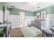Bedroom with board and batten trim, featuring two cribs, and soft green walls at 1634 Crittenden Ln, Lawrenceville, GA 30043