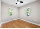 Bright bedroom featuring hardwood floors, ceiling fan, and two windows overlooking the yard at 1396 Elizabeth Ln, Atlanta, GA 30344
