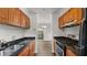 Galley kitchen features wooden cabinets, black countertops, stainless steel appliances, and hardwood style flooring at 49 Country Ct, Alpharetta, GA 30005