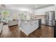 Open kitchen and living room, showcasing white cabinets, granite countertops, stainless appliances, and modern hardwood floors at 109 Camden Park Dr, Woodstock, GA 30188