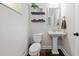 Well-lit powder room featuring a pedestal sink, a decorative mirror, and dark wood floors at 109 Camden Park Dr, Woodstock, GA 30188