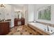 An inviting bathroom with a large soaking tub, vanity, and leaded-glass window at 119 Kennemer Ct, Johns Creek, GA 30097