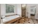 A relaxing bathroom featuring a soaking tub, a travertine tile shower, and leaded-glass window at 119 Kennemer Ct, Johns Creek, GA 30097