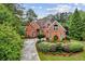 Stately red brick home with a well-maintained lawn, mature trees, and a long driveway, exuding curb appeal at 119 Kennemer Ct, Johns Creek, GA 30097