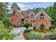 Beautiful red brick home with mature landscaping, arched windows, and a grand entrance, radiating classic elegance at 119 Kennemer Ct, Johns Creek, GA 30097