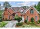 Charming red brick home featuring a well-manicured front yard, arched entryway, and plentiful windows for natural light at 119 Kennemer Ct, Johns Creek, GA 30097