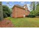 View of a brick home with a spacious backyard, deck, and mature trees, providing a private setting at 119 Kennemer Ct, Johns Creek, GA 30097
