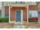 Charming brick facade with a welcoming gray front door, lush greenery, and manicured bushes at 8020 Woodland Ln, Alpharetta, GA 30009