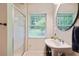 Bright bathroom featuring a single sink vanity, a window, and a shower with a sliding glass door at 2640 Spring Se Dr, Smyrna, GA 30080