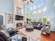 Bright living room with hardwood floors, a fireplace, built-in shelving, comfortable seating, and a two-story window view at 7060 Summit Ridge Chase, Cumming, GA 30041