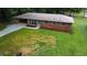 This aerial view shows the brick house with mature trees and the spacious lawn on the property at 191 Pine Ne St, Fairburn, GA 30213