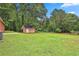 A sprawling green backyard with lush trees surrounding a wooden storage shed near the red brick home at 191 Pine Ne St, Fairburn, GA 30213