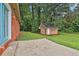 A spacious backyard featuring a brick home, concrete patio, and charming wooden storage shed at 191 Pine Ne St, Fairburn, GA 30213