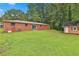 This home features a well-maintained lawn and a spacious backyard with a red brick home and shed at 191 Pine Ne St, Fairburn, GA 30213