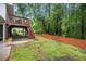 Spacious backyard with a wooden deck, stairs, patio, and a lush green lawn surrounded by mature trees at 2020 New Kemp Rd, Marietta, GA 30066